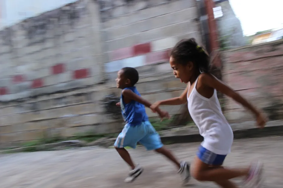 Two children racing along a wall, caught mid-stride