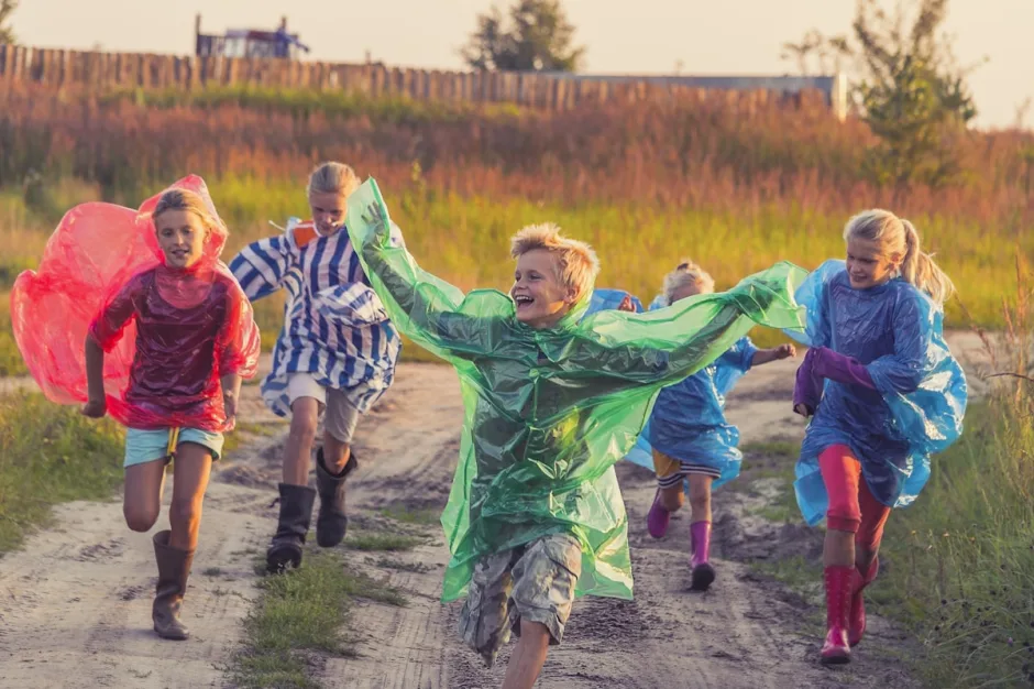 Children in colourful capes running together down a path